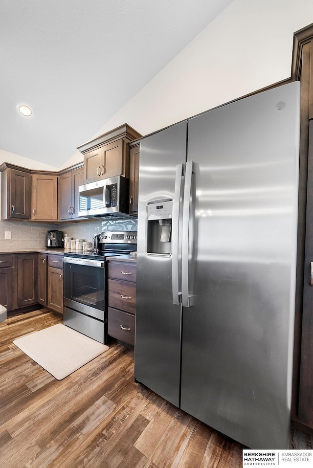 kitchen featuring tasteful backsplash, hardwood / wood-style flooring, vaulted ceiling, and appliances with stainless steel finishes