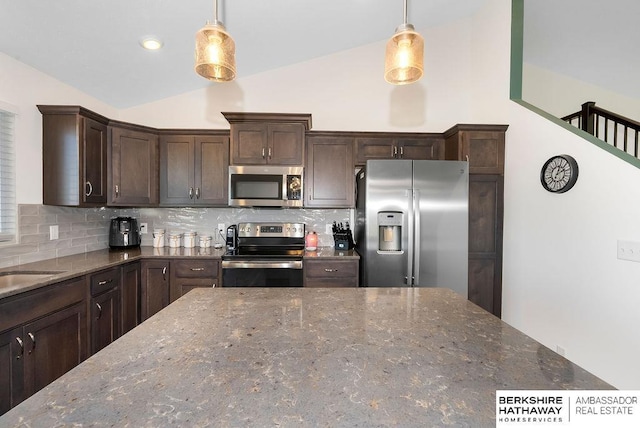 kitchen with dark stone countertops, stainless steel appliances, and hanging light fixtures