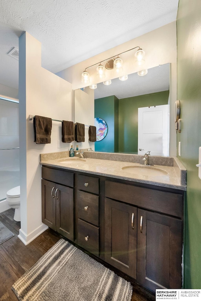 bathroom with an enclosed shower, toilet, a textured ceiling, vanity, and hardwood / wood-style flooring