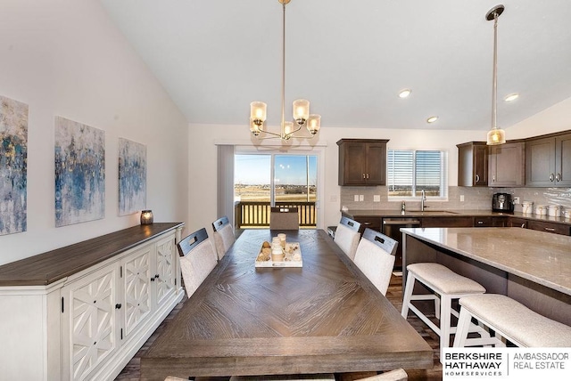 dining room with sink, vaulted ceiling, and a notable chandelier