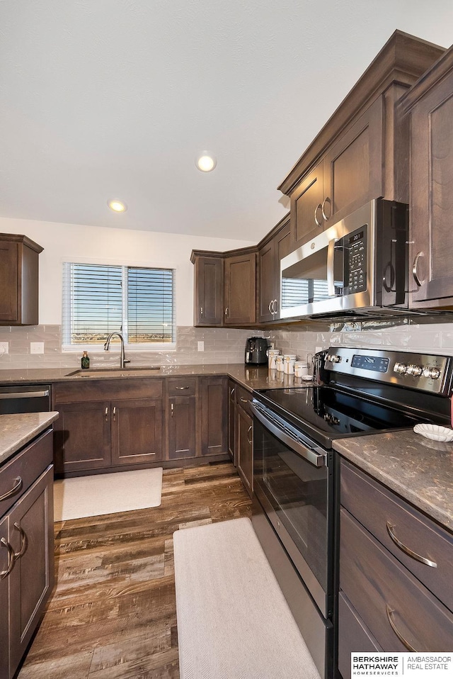 kitchen with dark hardwood / wood-style flooring, sink, backsplash, and appliances with stainless steel finishes