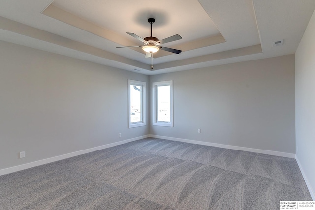 carpeted spare room with ceiling fan and a tray ceiling