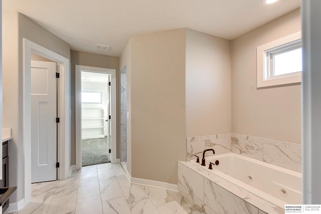 bathroom with vanity and tiled tub