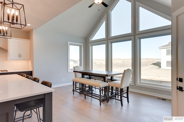 dining space featuring lofted ceiling, ceiling fan with notable chandelier, and light hardwood / wood-style flooring