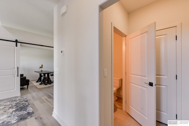 hall featuring a barn door and light hardwood / wood-style flooring