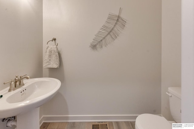 bathroom with toilet, wood-type flooring, and sink