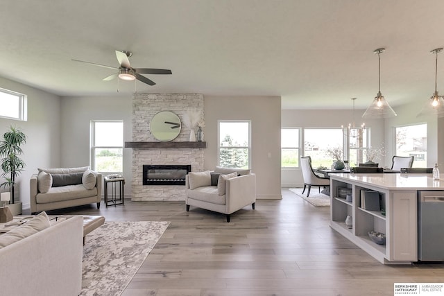 living room with a fireplace, ceiling fan with notable chandelier, and light hardwood / wood-style floors