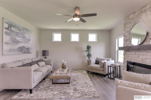 living room featuring hardwood / wood-style flooring, ceiling fan, and a fireplace