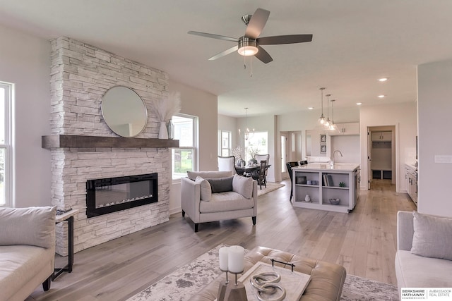 living room with hardwood / wood-style flooring, ceiling fan, and a stone fireplace