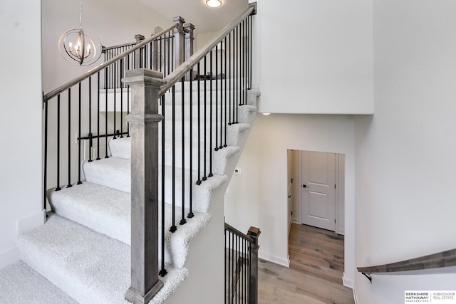 stairway with wood-type flooring and a chandelier