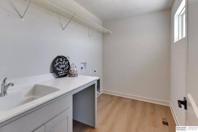 laundry area with hookup for an electric dryer, washer hookup, light hardwood / wood-style flooring, and sink