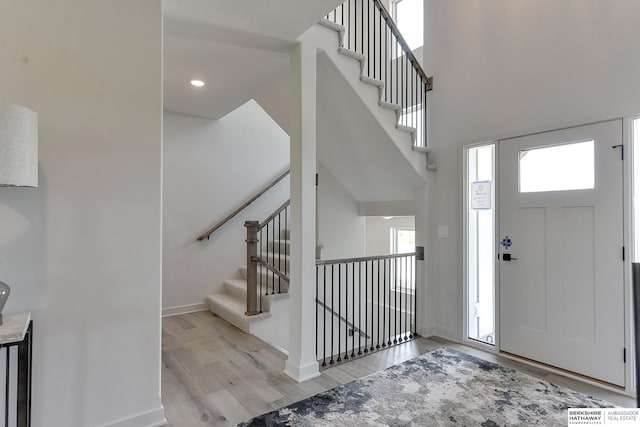 foyer entrance with a towering ceiling and light hardwood / wood-style floors