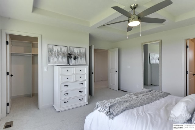 carpeted bedroom with a raised ceiling, ceiling fan, beam ceiling, a spacious closet, and a closet