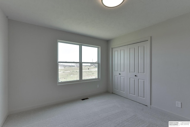 unfurnished bedroom featuring a closet and light colored carpet