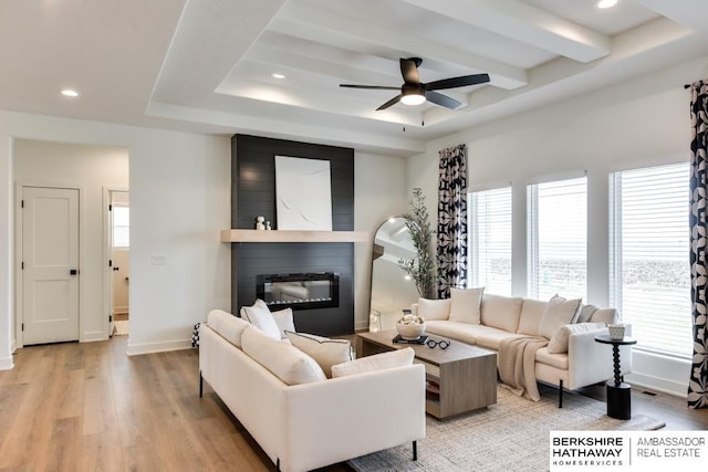 living room featuring ceiling fan, light hardwood / wood-style floors, a healthy amount of sunlight, and a fireplace