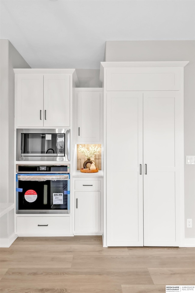 kitchen featuring white cabinets, decorative backsplash, light hardwood / wood-style floors, and appliances with stainless steel finishes