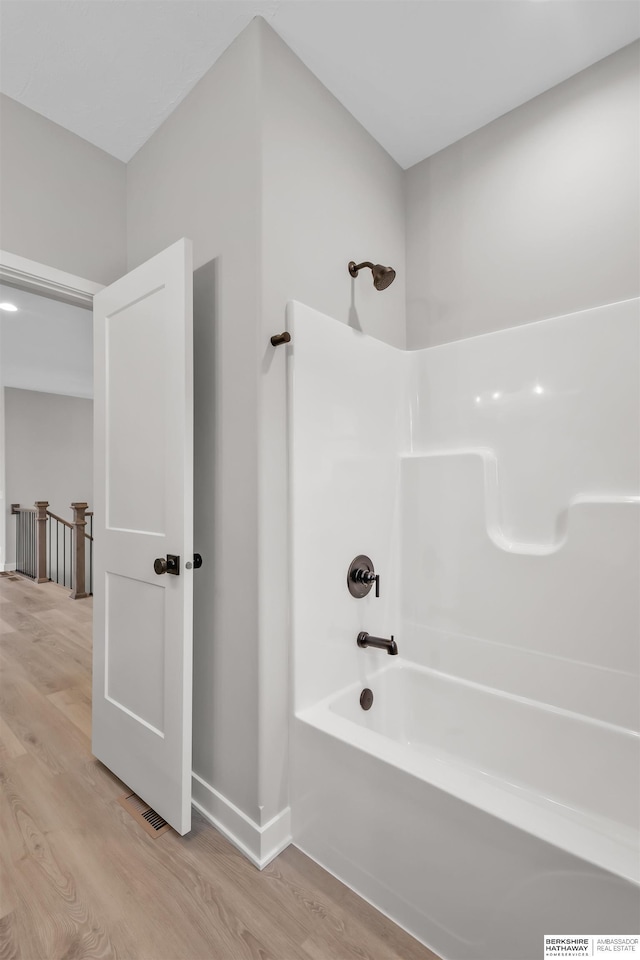 bathroom featuring wood-type flooring and shower / washtub combination