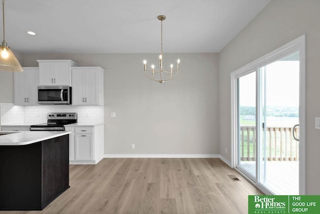 kitchen with an inviting chandelier, decorative backsplash, appliances with stainless steel finishes, decorative light fixtures, and white cabinetry