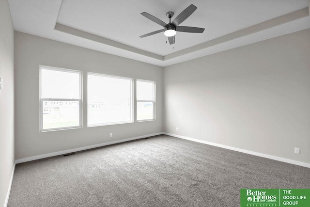 unfurnished room with a raised ceiling, ceiling fan, and carpet floors