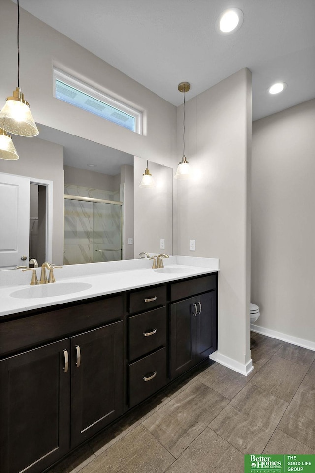 bathroom with a shower with door, vanity, and toilet