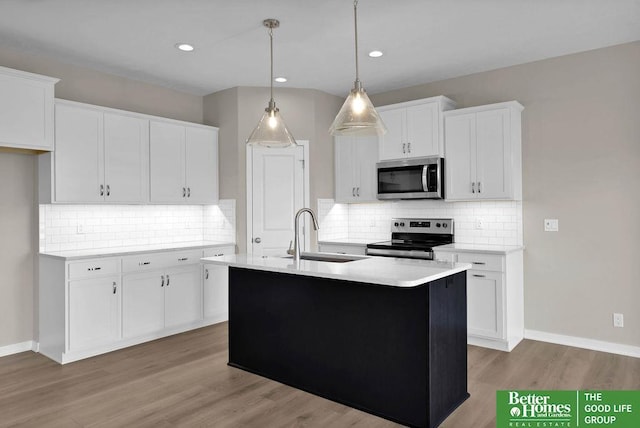 kitchen featuring white cabinets, appliances with stainless steel finishes, a kitchen island with sink, and sink