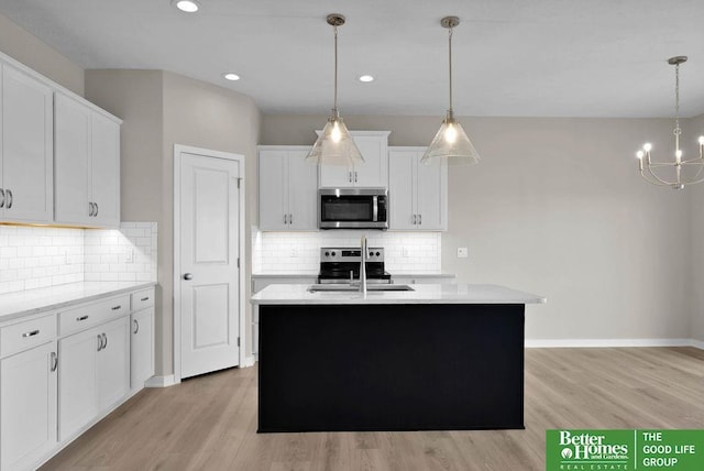 kitchen featuring white cabinetry, an inviting chandelier, pendant lighting, a center island with sink, and appliances with stainless steel finishes