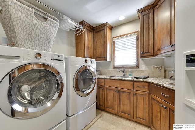 clothes washing area with cabinets, sink, and washer and dryer