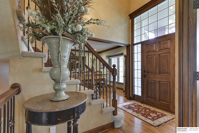 foyer featuring hardwood / wood-style flooring, a towering ceiling, and crown molding