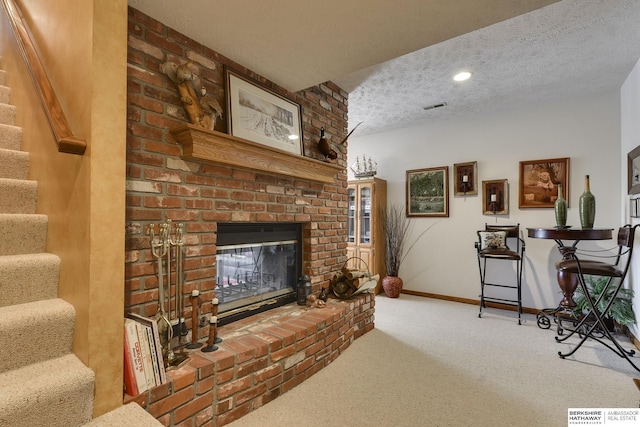 carpeted living room with a fireplace and a textured ceiling