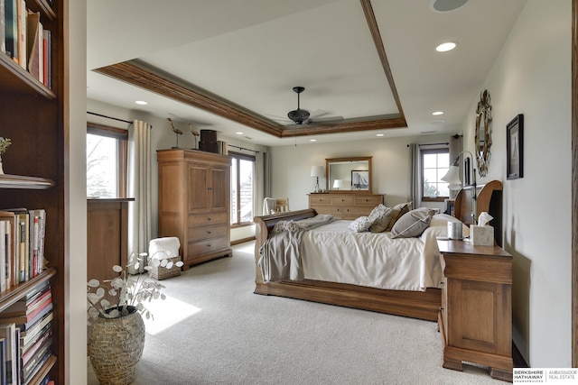 bedroom with light carpet, a tray ceiling, ceiling fan, and crown molding