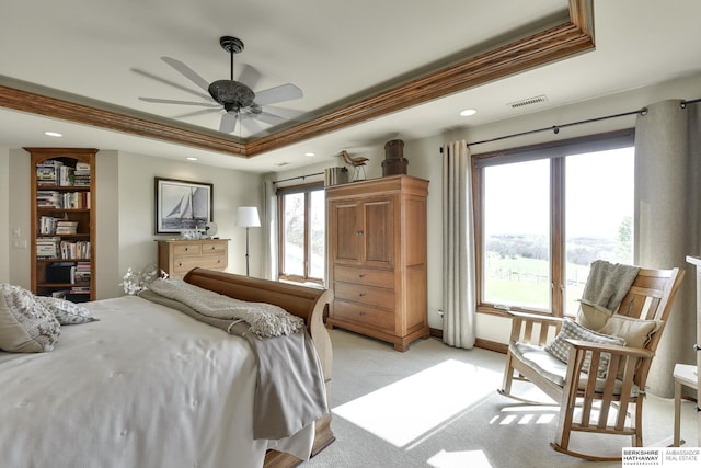 bedroom with ceiling fan, a raised ceiling, light colored carpet, and multiple windows