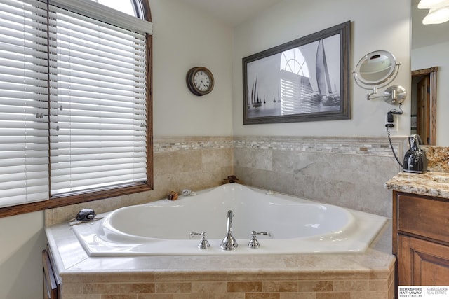 bathroom with vanity and tiled bath