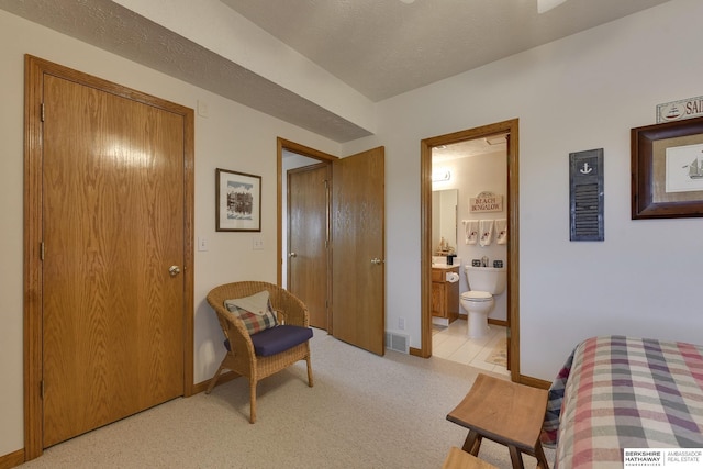 bedroom featuring connected bathroom and light colored carpet