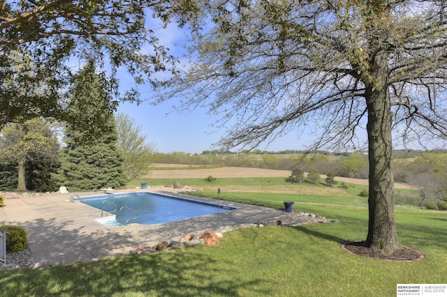 view of swimming pool featuring a yard, a rural view, a diving board, and a patio area