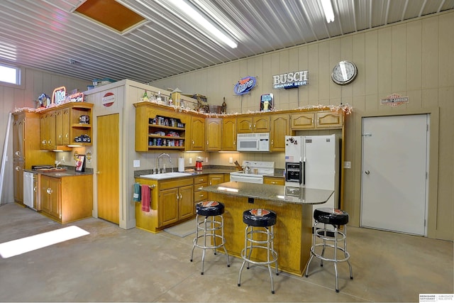 kitchen featuring a kitchen bar, white appliances, a center island, and sink