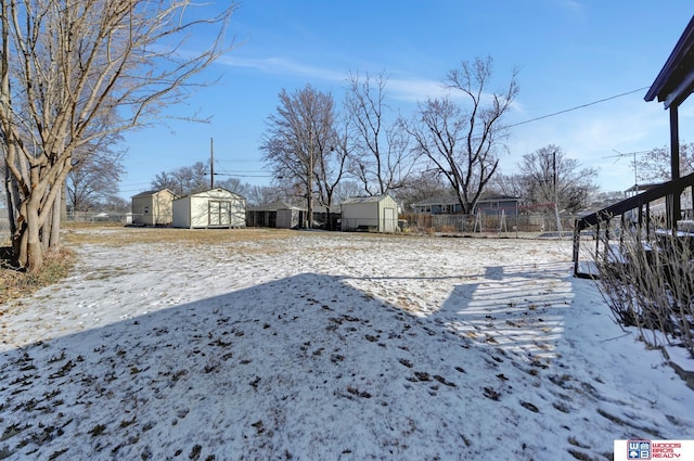 snowy yard featuring a storage unit