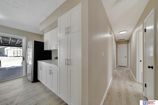 kitchen featuring white cabinets, stainless steel refrigerator with ice dispenser, and light wood-type flooring