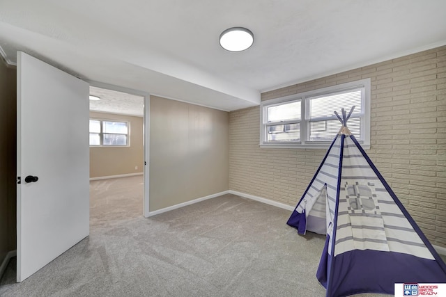 playroom with carpet flooring and brick wall