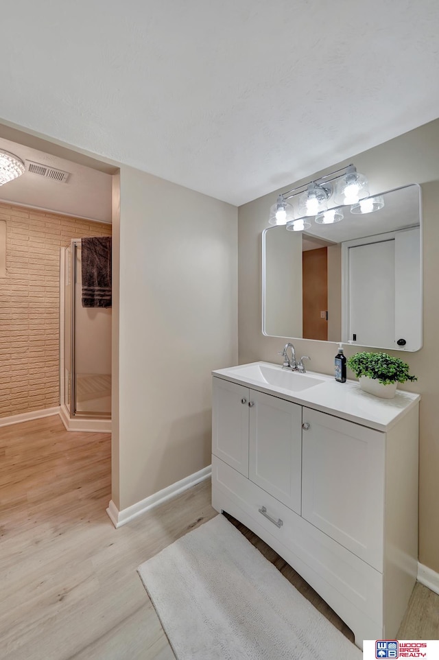 bathroom featuring hardwood / wood-style flooring, vanity, and an enclosed shower