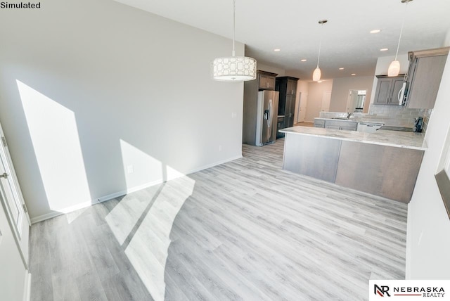 kitchen featuring backsplash, kitchen peninsula, hanging light fixtures, light wood-type flooring, and stainless steel fridge with ice dispenser