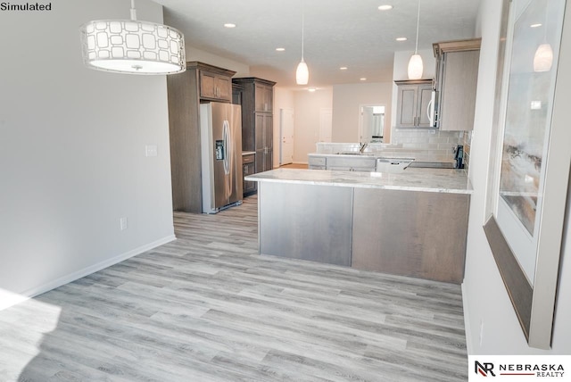 kitchen with decorative backsplash, kitchen peninsula, sink, stainless steel fridge with ice dispenser, and hanging light fixtures