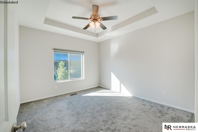 unfurnished room with a tray ceiling, ceiling fan, and light colored carpet