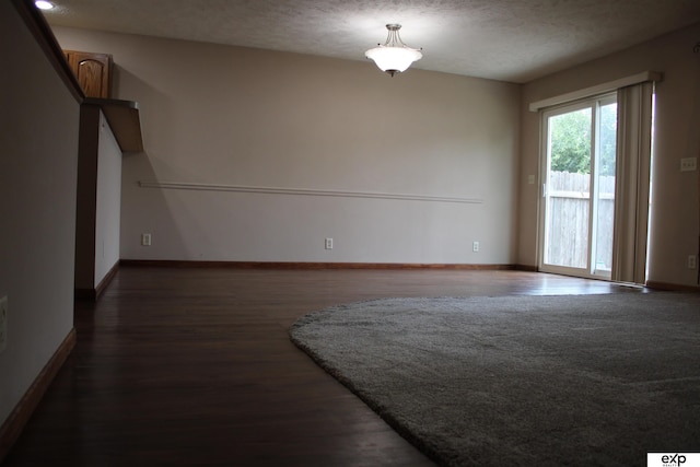 empty room with dark hardwood / wood-style floors and a textured ceiling