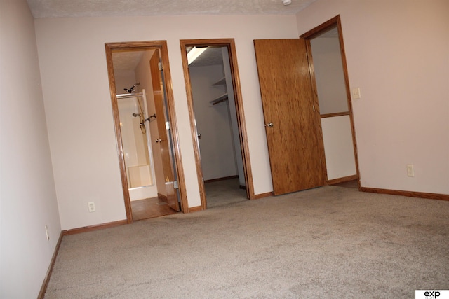 unfurnished bedroom with a walk in closet, light colored carpet, a closet, and a textured ceiling