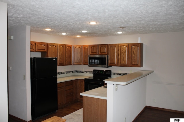 kitchen featuring dark hardwood / wood-style floors, black appliances, kitchen peninsula, and a textured ceiling