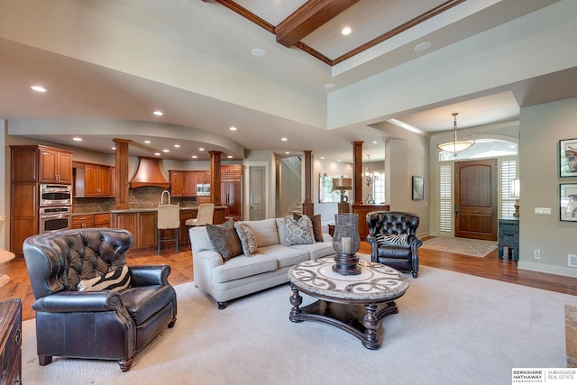 living room featuring beamed ceiling, a healthy amount of sunlight, crown molding, and light hardwood / wood-style flooring