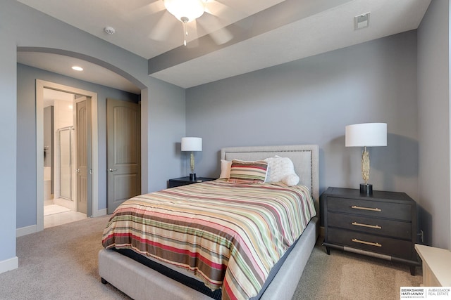 bedroom with ceiling fan, light colored carpet, and ensuite bathroom