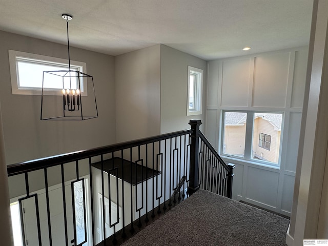 stairs with carpet flooring, a chandelier, and a healthy amount of sunlight