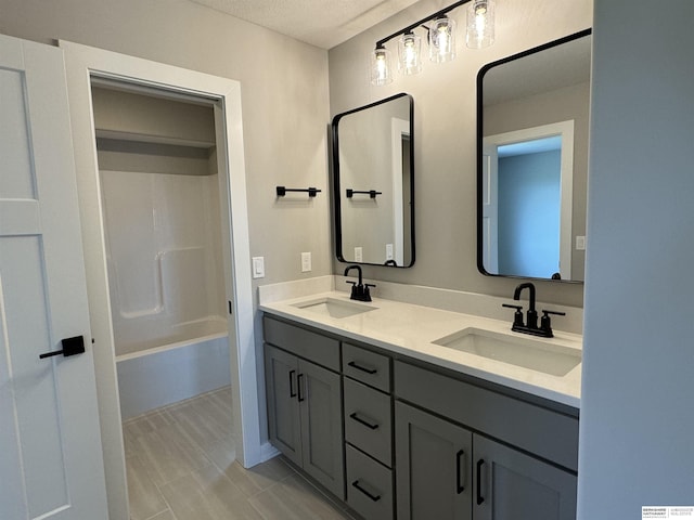 bathroom with a textured ceiling, tub / shower combination, and vanity