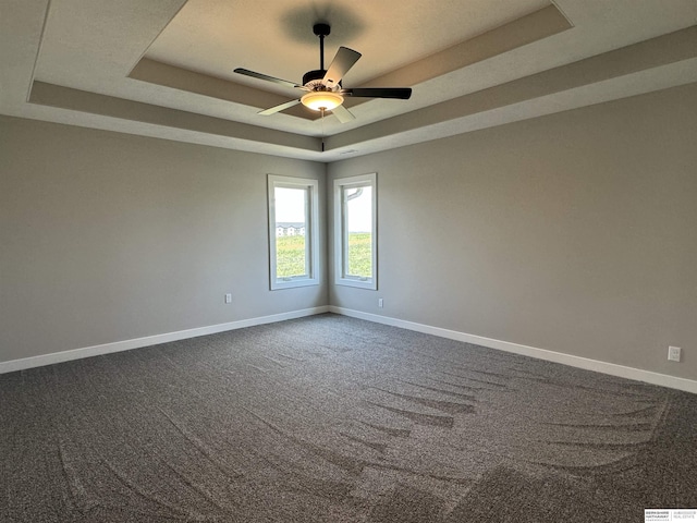 carpeted spare room featuring ceiling fan and a tray ceiling